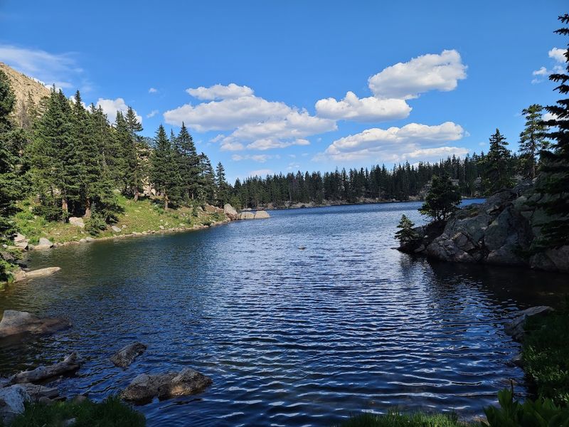 A Quiet Basin Framed By Forest And Sky
