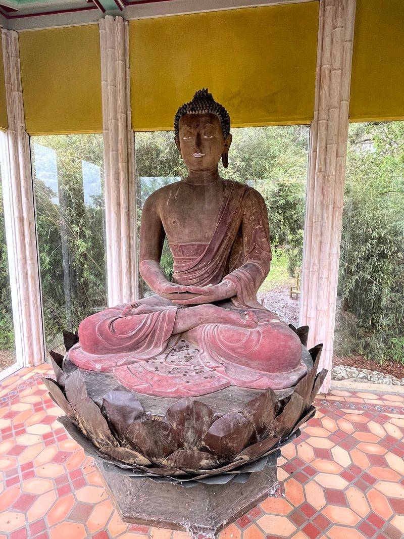 An Ancient Buddha Rests Peacefully Among The Camellias